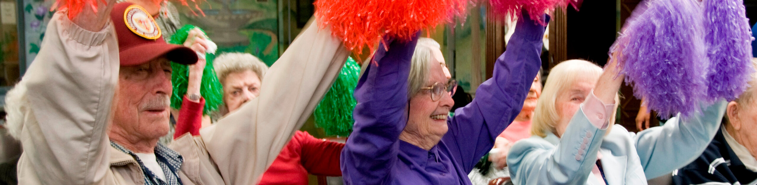 Seniors cheering with colorful pom-poms, enjoying an activity in a lively setting